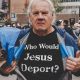 A man at a protest wearing a shirt with the text "who would jesus deport?" while holding a megaphone.