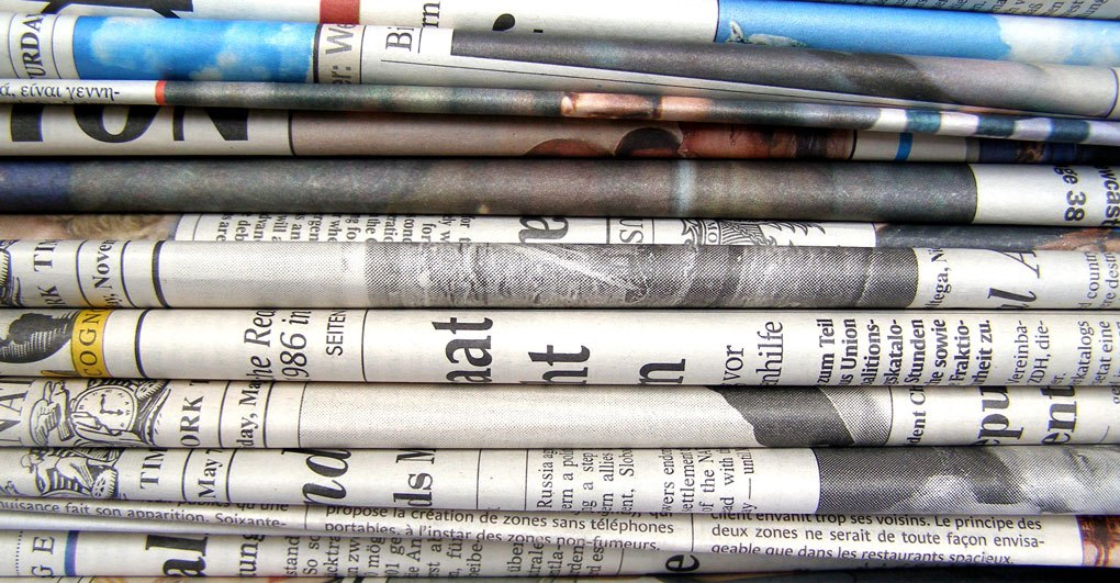 A stack of various newspapers folded and arranged closely together.