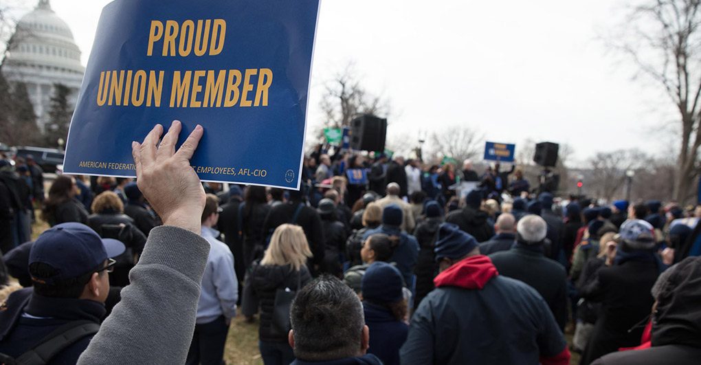 A person holding up a sign that says "proud union member" at a gathering, possibly during a union rally or event.