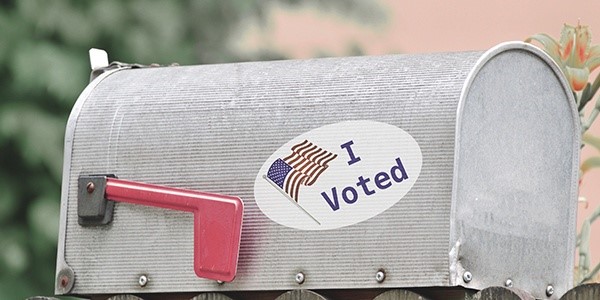 A mailbox adorned with an "i voted" sticker featuring an american flag design.